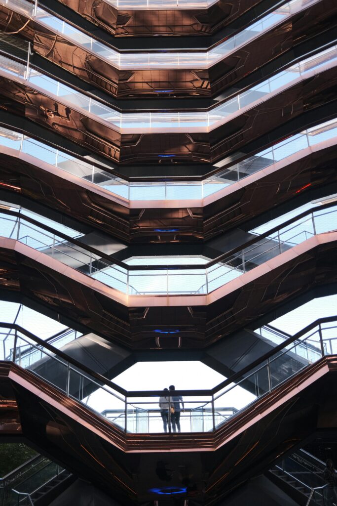 Dramatic view of the Vessel's intricate architecture in NYC with two people.