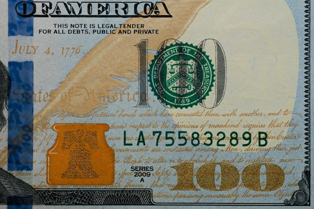 Detailed view of a US 100 dollar bill highlighting security features and design elements.