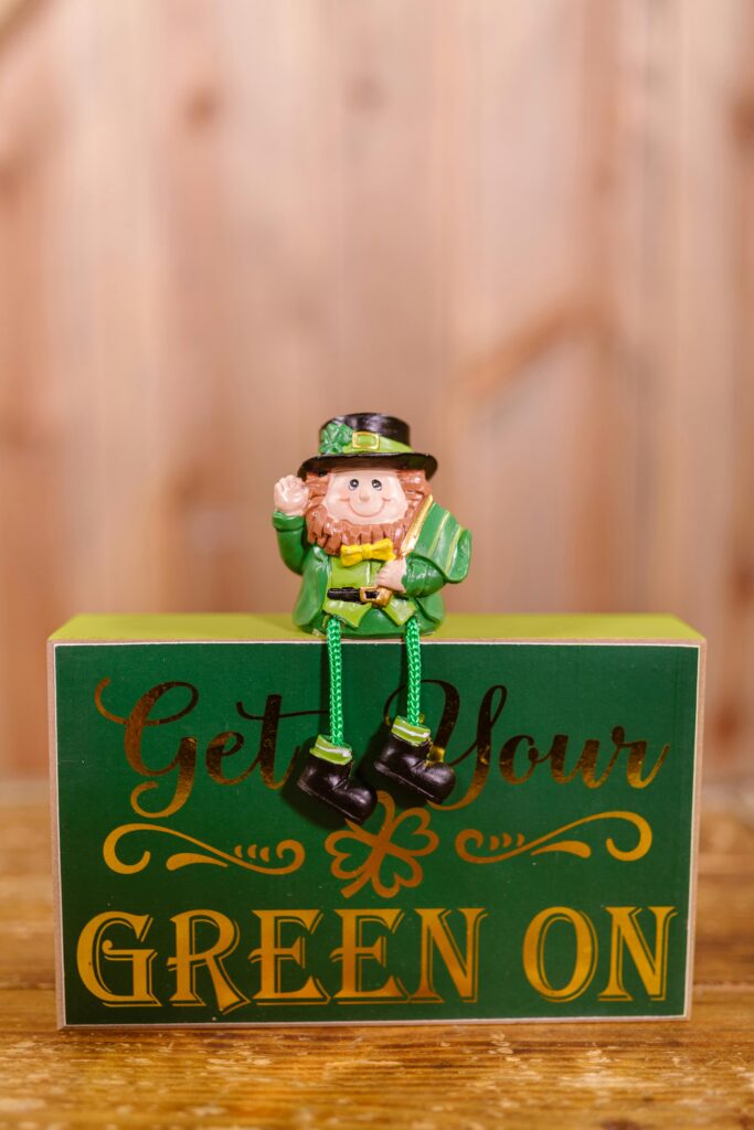 A cheerful leprechaun figurine sits on a St. Patrick's Day themed sign.